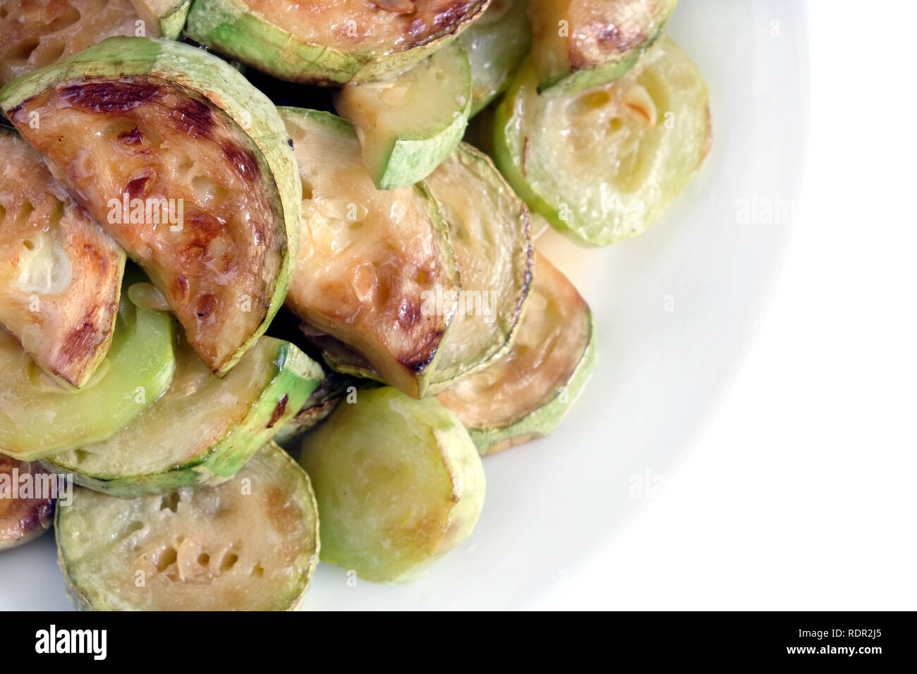 Molti fritti fette di zucchine sul round piastra bianca su sfondo bianco studio shot top view closeup Foto Stock