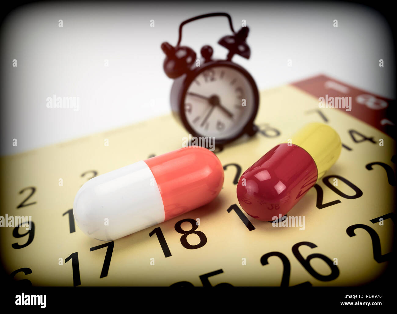 Pillole su un calendario lungo con un orologio, immagine concettuale Foto Stock