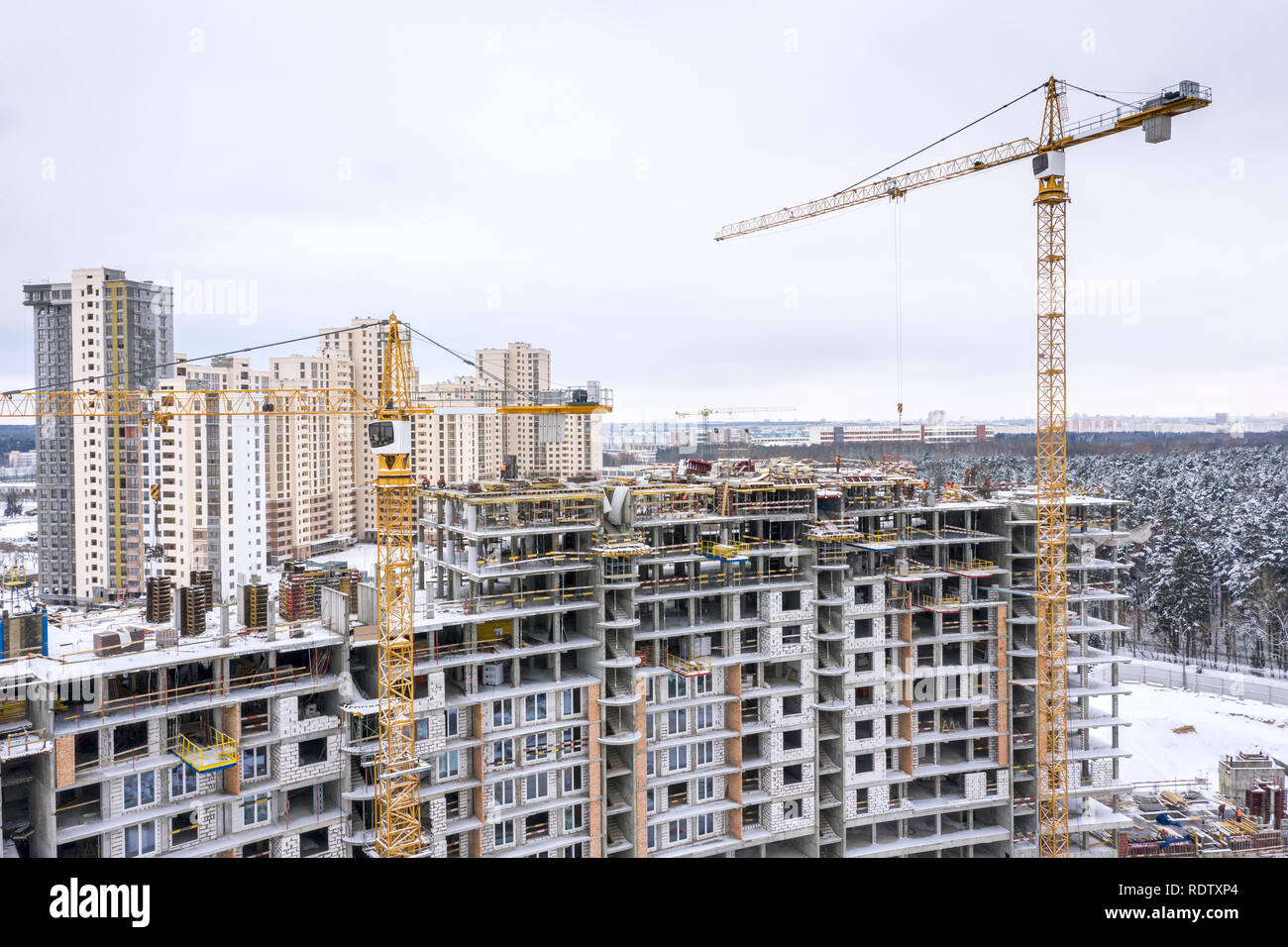 Antenna vista panoramica della città di costruzione sito in inverno. gialla gru a torre la costruzione di nuovi appartamenti residenziali Foto Stock