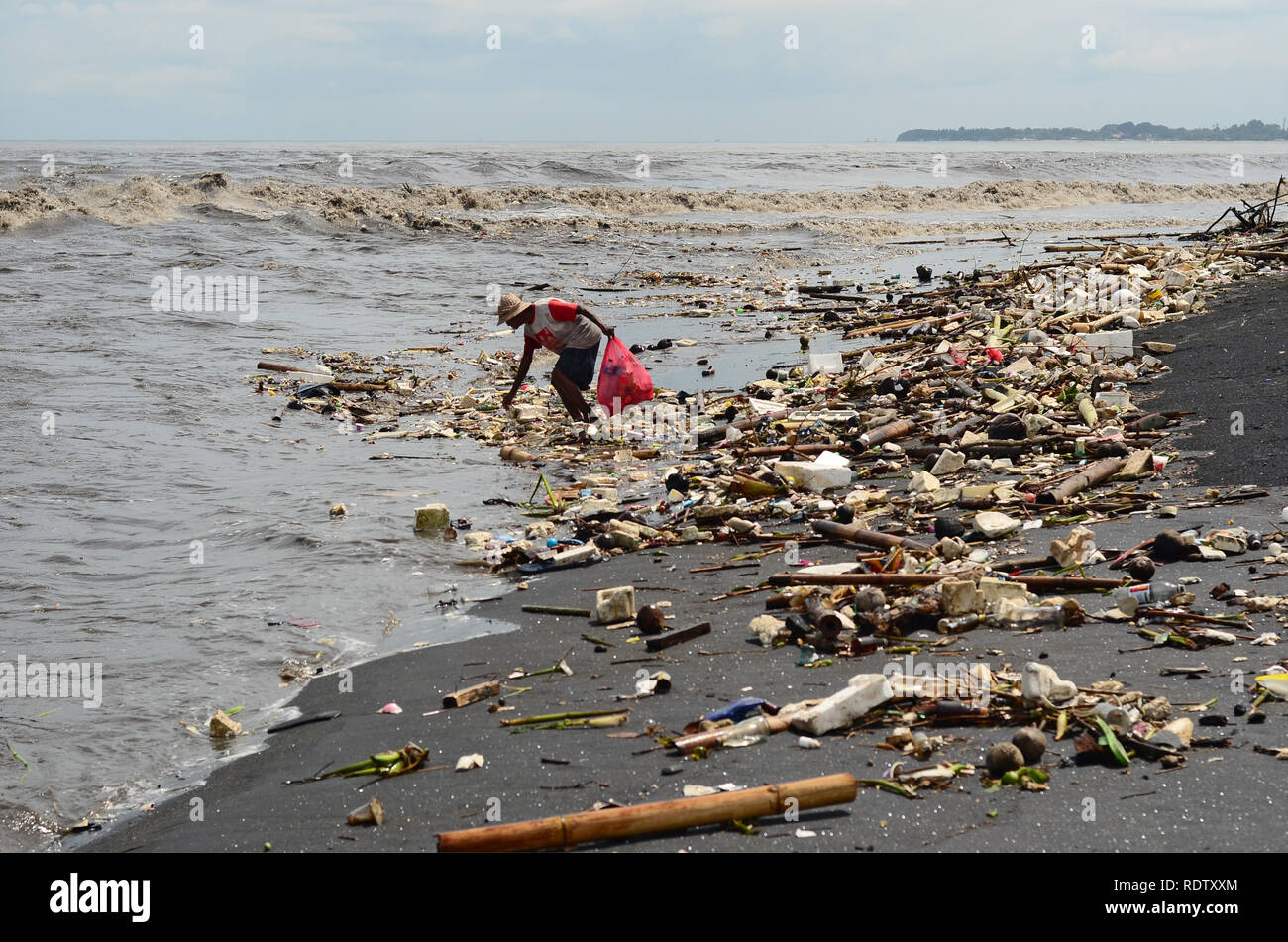 La gente a raccogliere la spazzatura a Bali Beach durante il monsone Foto Stock