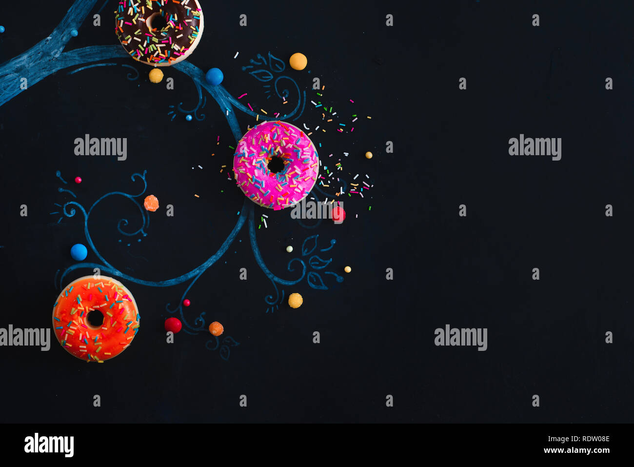 Le ciambelle che cresce su un disegno di gesso di un albero. Tasto basso cibo laici piana. Concetto creativo con copia spazio. Foto Stock