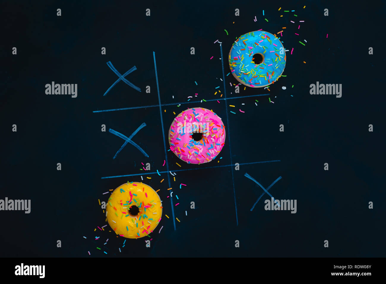 Ciambelle vetrato tic-tac-toe gioco. Chalk disegno su sfondo scuro con copia spazio. Cucina creativa laici piana. Foto Stock