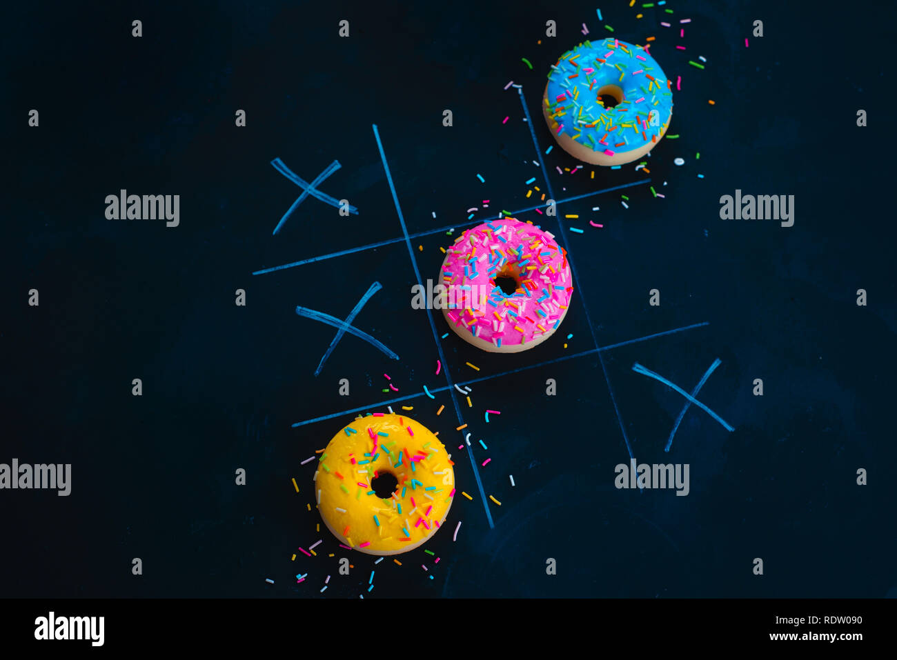 Ciambelle vetrato tic-tac-toe gioco. Chalk disegno su sfondo scuro con copia spazio. Cucina creativa laici piana. Foto Stock