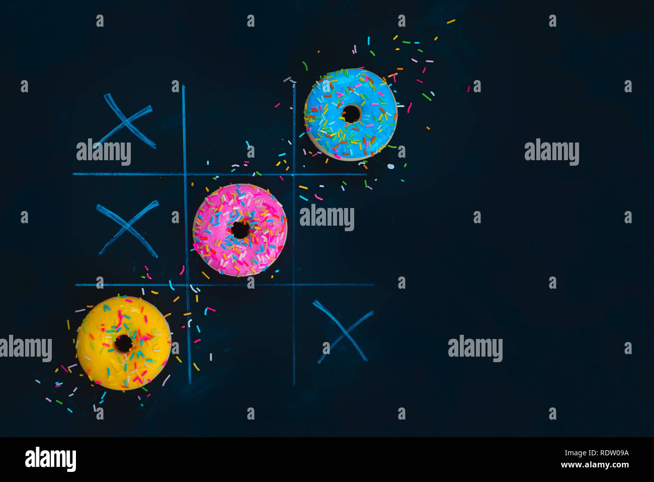 Ciambelle vetrato tic-tac-toe gioco. Chalk disegno su sfondo scuro con copia spazio. Cucina creativa laici piana. Foto Stock