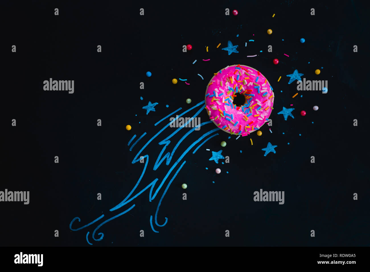 Spazio ciambella con un gesso disegno di una stella cadente, coda di cometa e stelle. Piatto cibo laici fotografia creativa. testata Vetri rosa Foto Stock