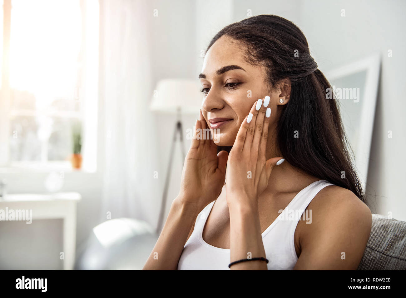 Rilassati con la pelle scura ragazza facendo massaggio su viso Foto Stock