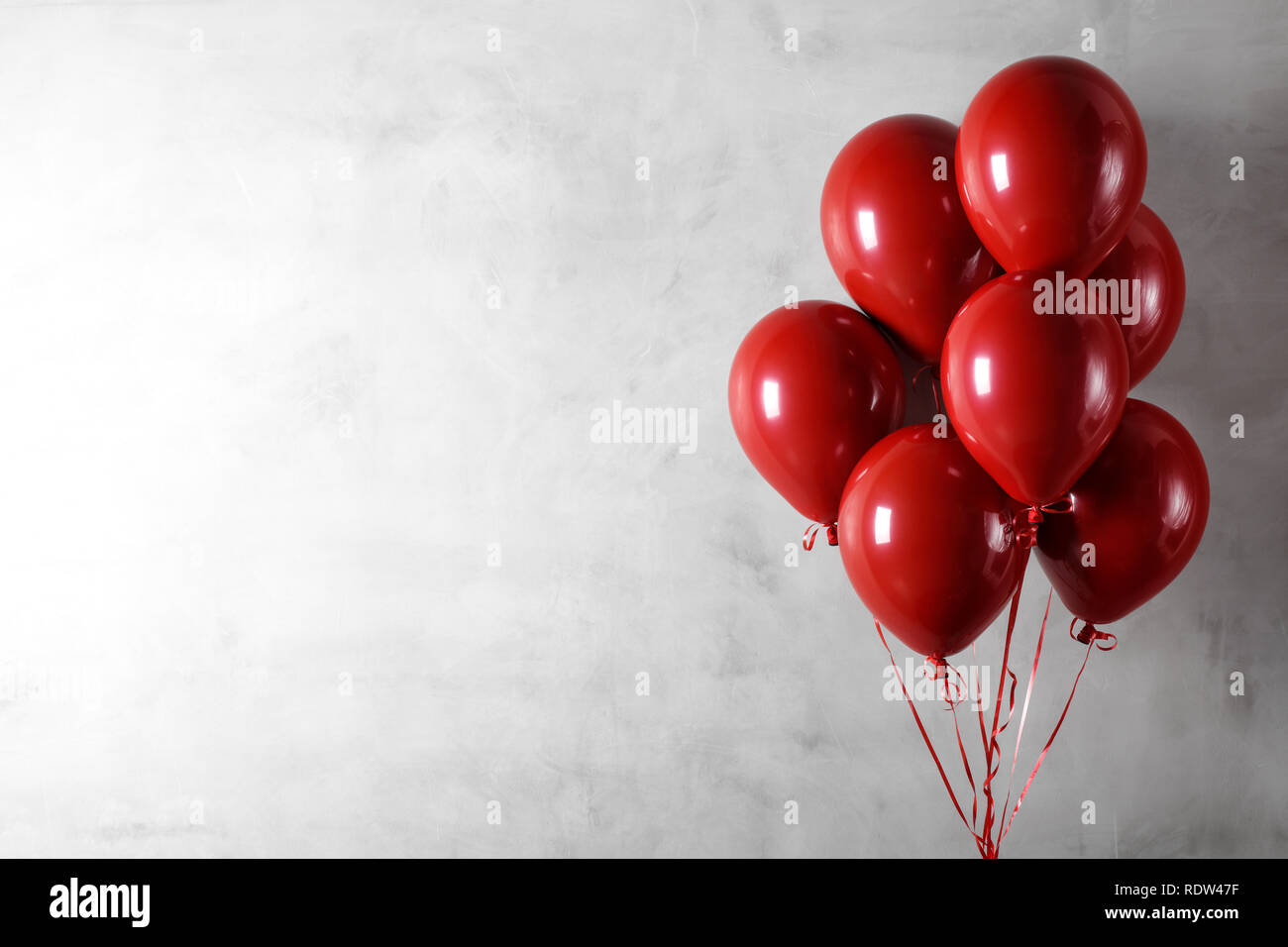 Grappolo di palloncini rossi sulla parete di cemento sullo sfondo Foto Stock