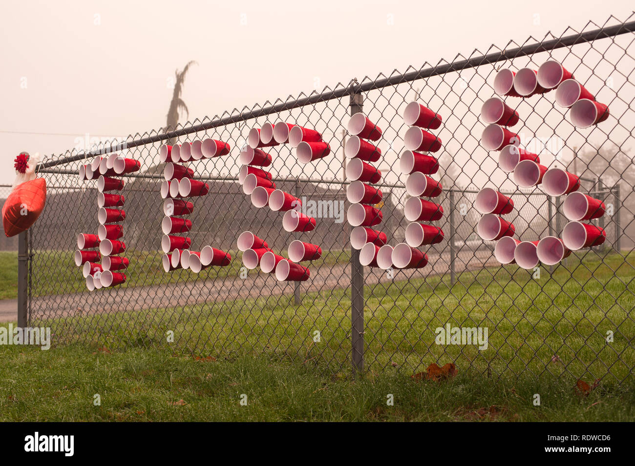 Red tazze di ortografia Gesù sulla catena collegamento recinto Foto Stock