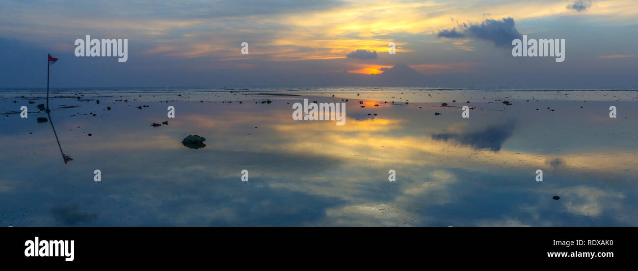 Foto panoramiche del tramonto in serata con una riflessione sull'acqua Indonesia Gilli Travangan Foto Stock