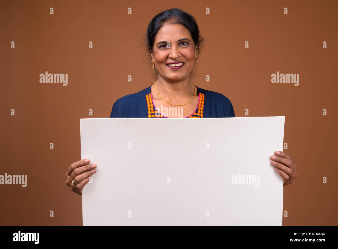 Felice donna indiana holding vuoto lavagna bianca con copyspace Foto Stock