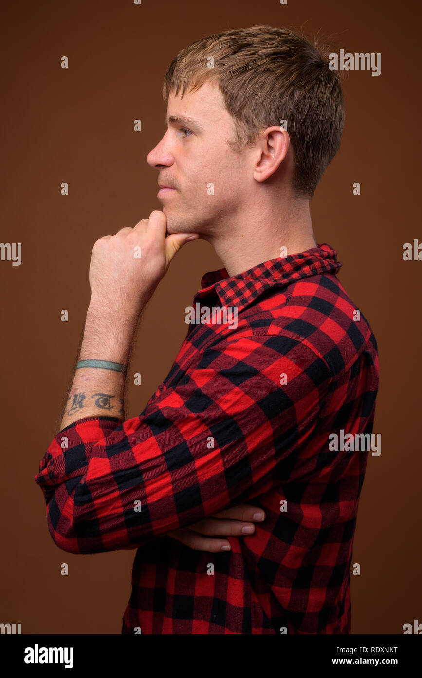 Vista di profilo di uomo che indossa rosso a scacchi shirt mentre pensando Foto Stock
