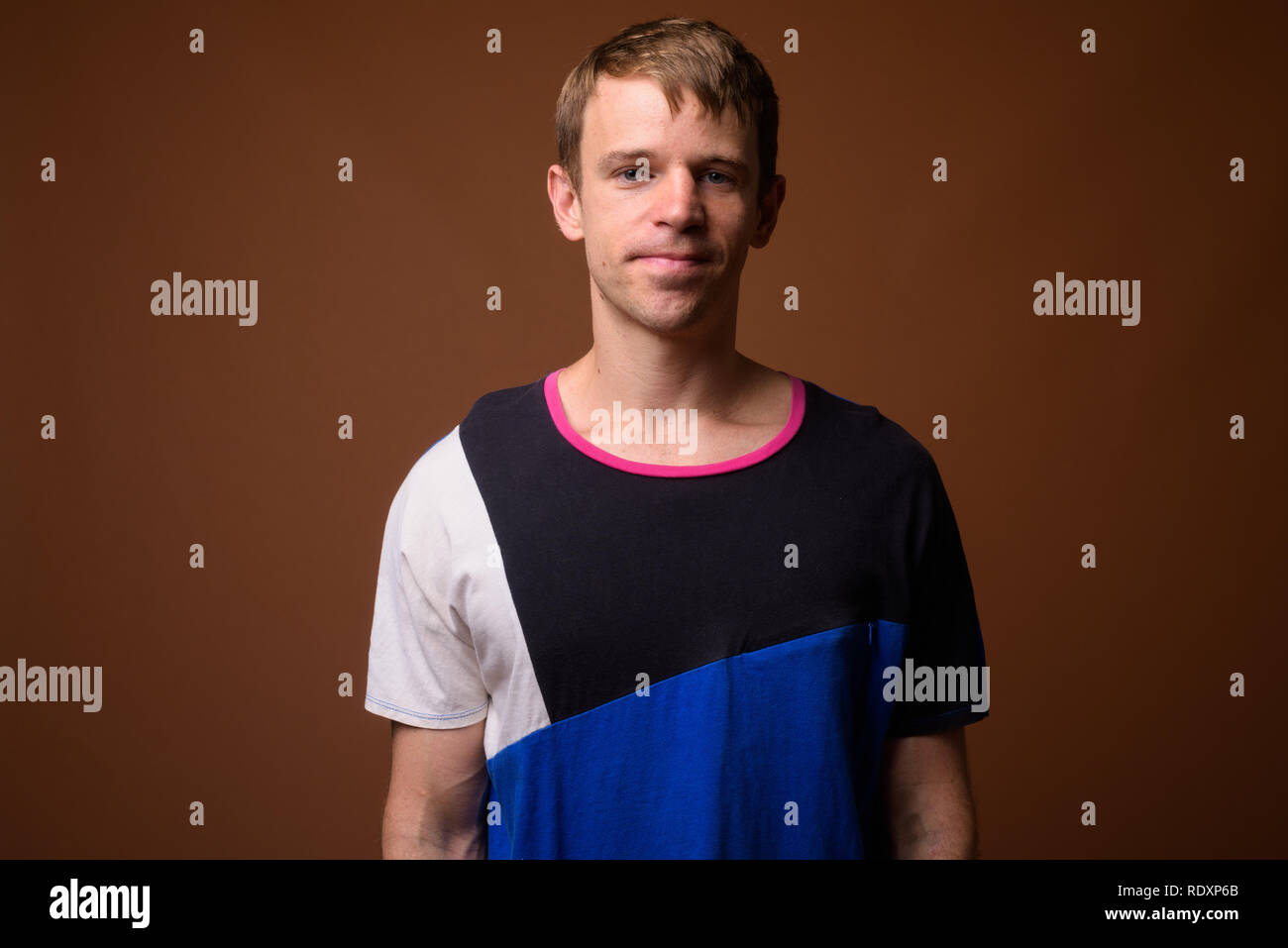Uomo che indossa maglietta blu contro sfondo marrone Foto Stock