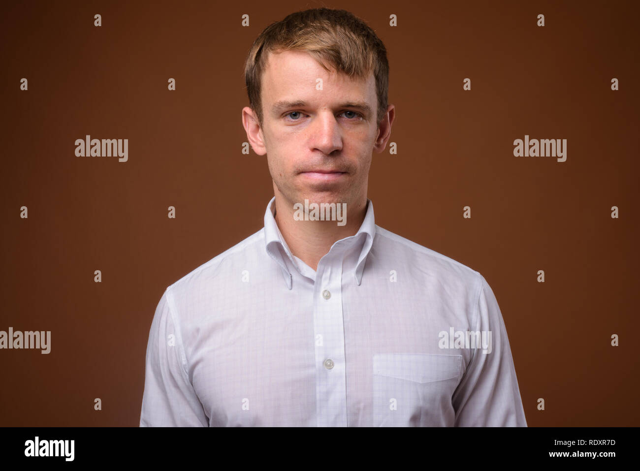 Imprenditore che indossa una camicia bianca contro lo sfondo marrone Foto Stock
