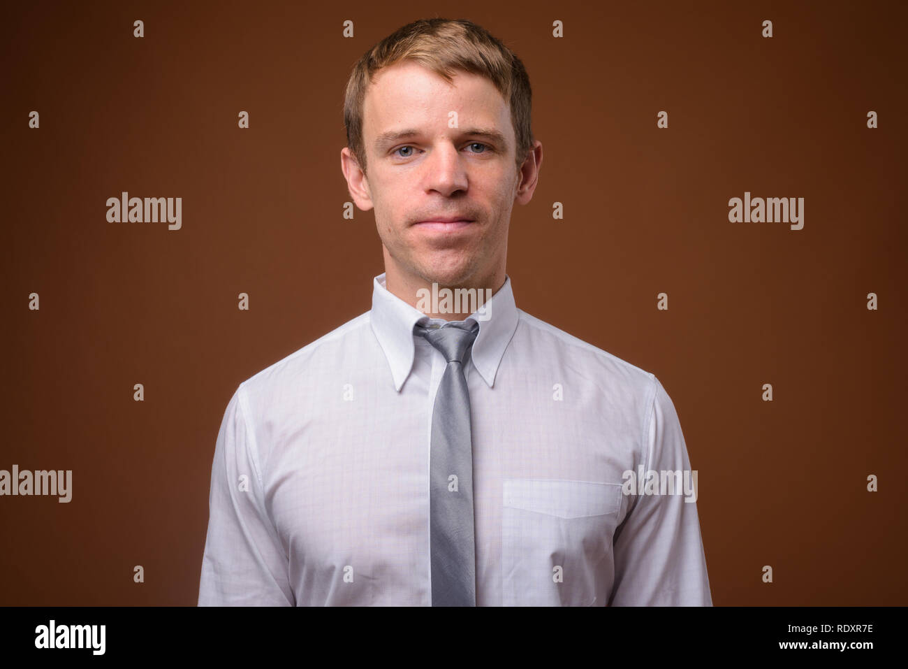 Imprenditore che indossa una camicia bianca contro lo sfondo marrone Foto Stock