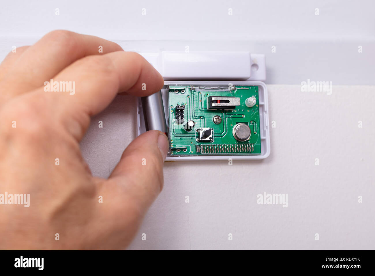 Close-up di un tecnico la mano che fissa il sistema di sicurezza del sensore della porta Foto Stock