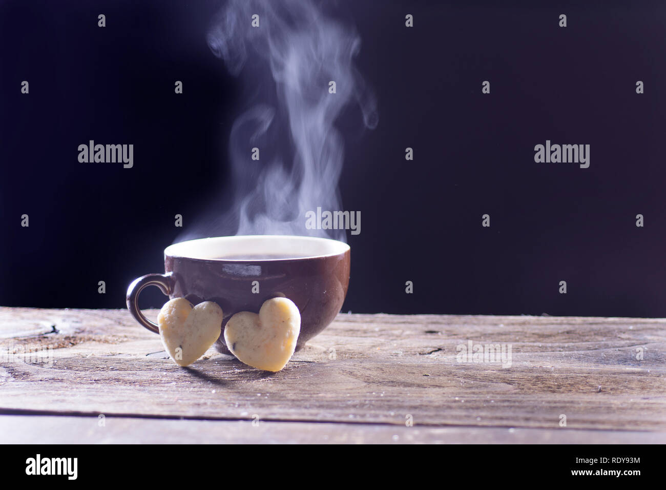Fumante tazza di caffè nero con due a forma di cuore i cookie Foto Stock