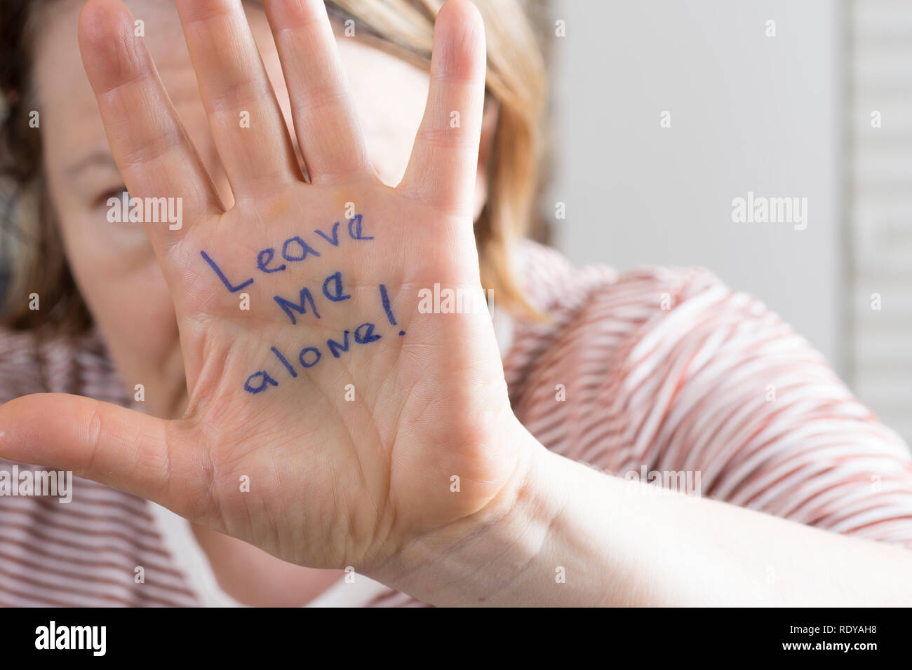 Una donna che si protegge con una mano avanzata che recita "Lascia solo me!" Foto Stock
