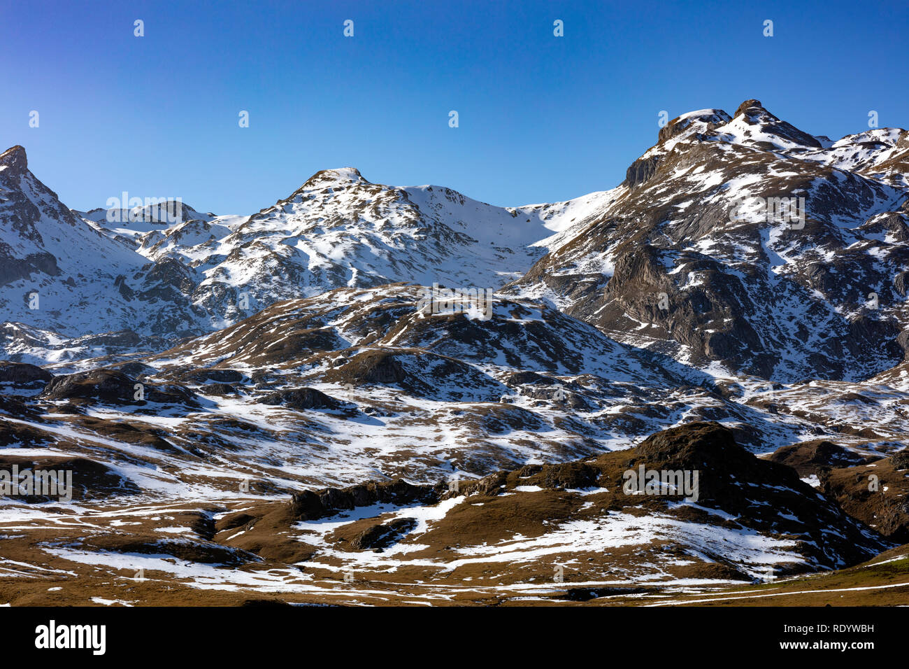 Montagne innevate paesaggio che mostra la prima neve su marrone erba durante i mesi invernali con un blu e il cielo chiaro Foto Stock