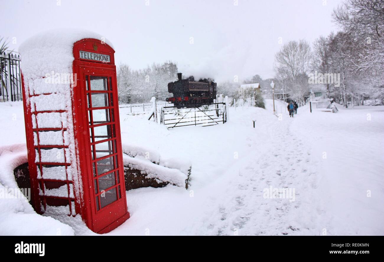 Telefono rosso scatola e treno a vapore nella neve Foto Stock