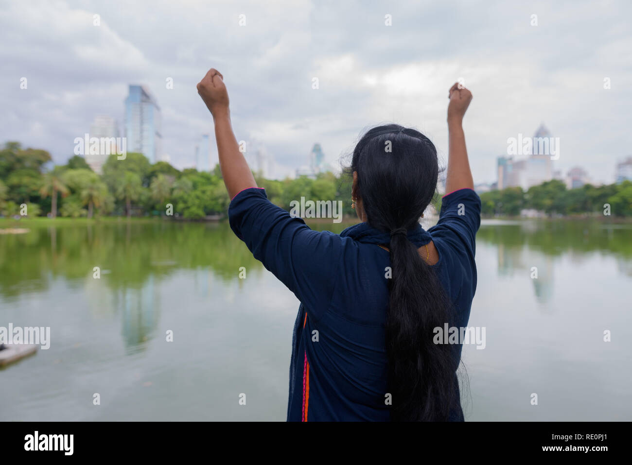 Vista posteriore della donna indiana con le braccia sollevate nel Parco Lumpini Foto Stock