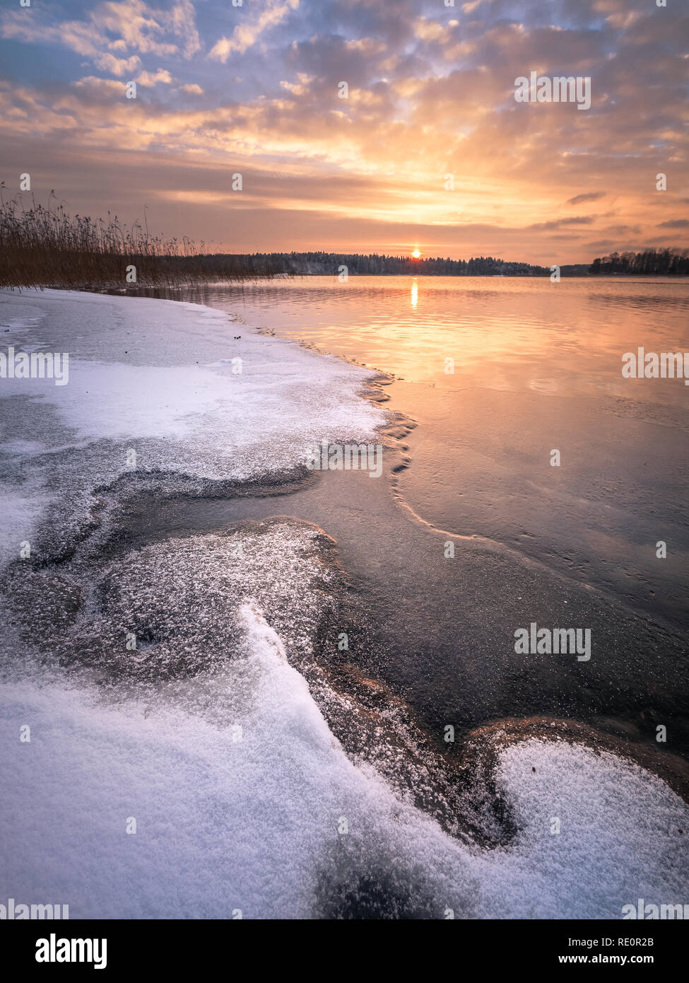 Scenic paesaggio invernale con lago ghiacciato e il tramonto in serata in Finlandia Foto Stock