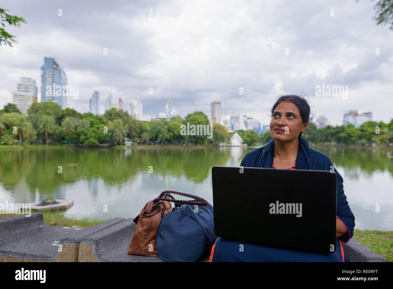 Ritratto di coppia donna indiana a park utilizzando il computer portatile Foto Stock