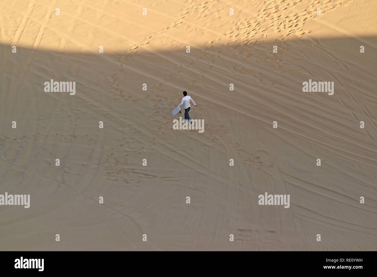 L'uomo con la sua scheda di sabbia a piedi su Huacachina deserto, Regione di Ica, Perù, Sud America Foto Stock