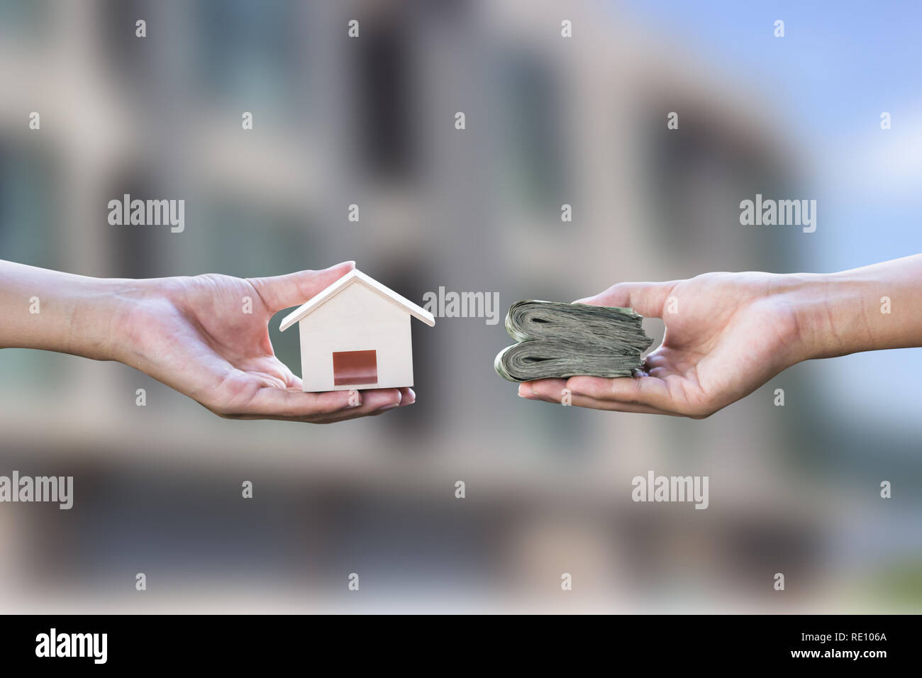 Home loan, ipoteche, debito, home concetto di acquisto. Mano azienda piccola residente lo scambio di denaro su sfocato immobiliare di sfondo. Scambio di finanzia un Foto Stock