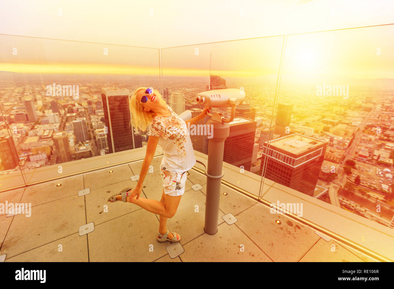 Donna traveler godendo al binocolo da Oue Skyspace Torre della banca in Los Angeles, California, Stati Uniti alla luce del tramonto. Felice turistico a terrazza panoramica sopra il centro di La skyline. Foto Stock