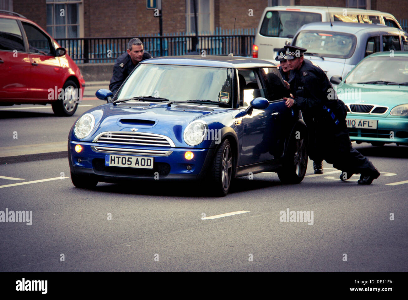 Tre inglesi ufficiali della polizia in uniforme spingendo una Mini Cooper dopo una rottura dalla corsia di destra in direzione di un più adeguato sistema di spot - Londra, Regno Unito Foto Stock