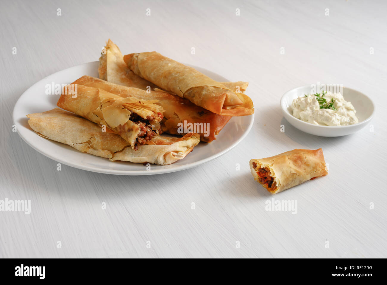 Filo o yufka rotoli di pasta farcita con un piccante ripieno di carne e il formaggio su un dipinto di bianco di tavola, spazio copia selezionata, focus, esigua profondità di fiel Foto Stock