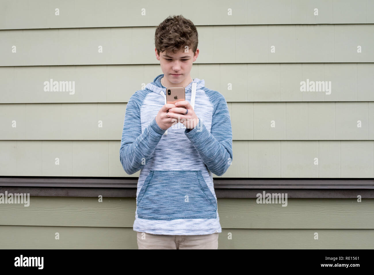Ragazzo adolescente texting sul suo nuovo Apple iPhone x Foto Stock