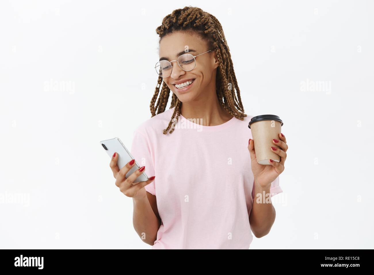 Socievole e comunicativa di buona ricerca moderna di carnagione scura studentessa con dreadlocks in rosa t-shirt e bicchieri di carta di contenimento tazza di caffè e tex Foto Stock
