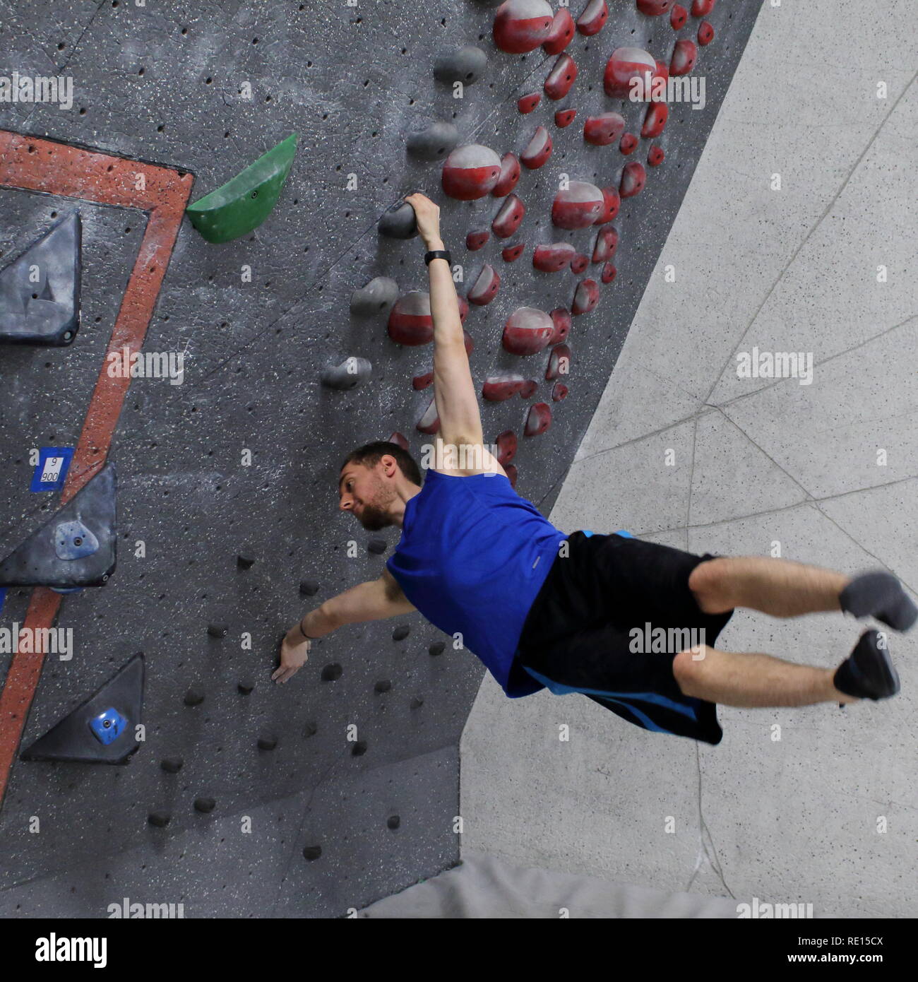 Scalatore eseguendo pennone sulla parete di arrampicata boulder Foto Stock