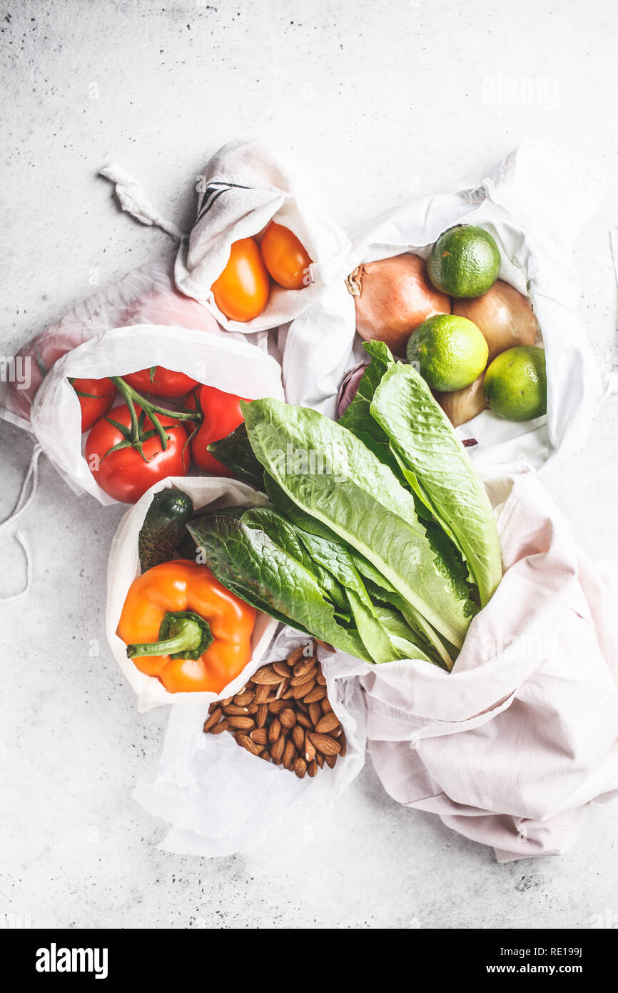 Verdure in eco borse in cotone, peperoni, pomodori, lattuga, cetriolo, calce, cipolla su sfondo bianco. Rifiuti Zero shopping alimentare. Foto Stock