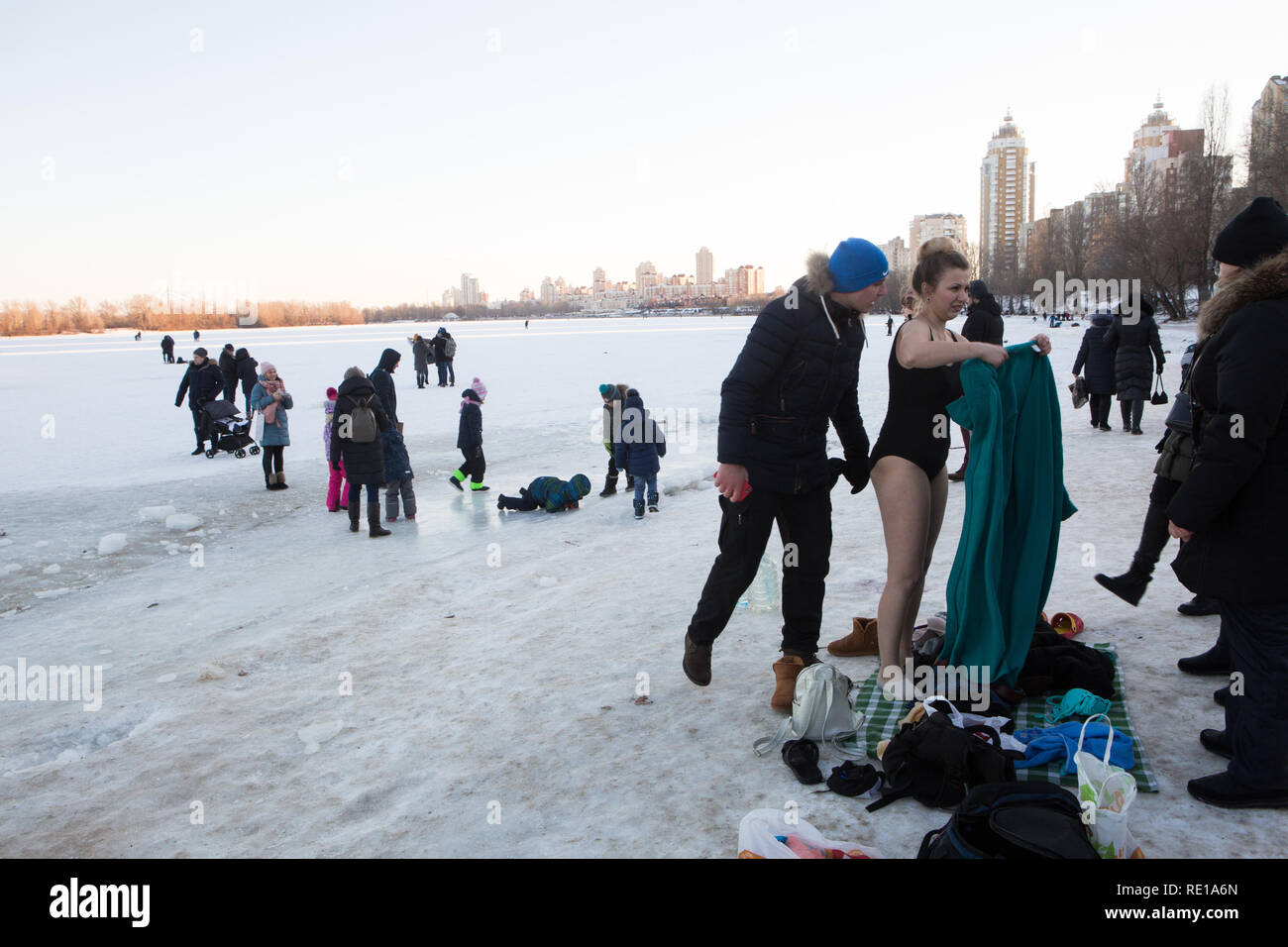 Famiglia ucraina sulla mattina di gennaio si prepara per un tuffo in acqua fredda con la giovane donna già in costume da bagno e un uomo scherzi circa il vento Foto Stock