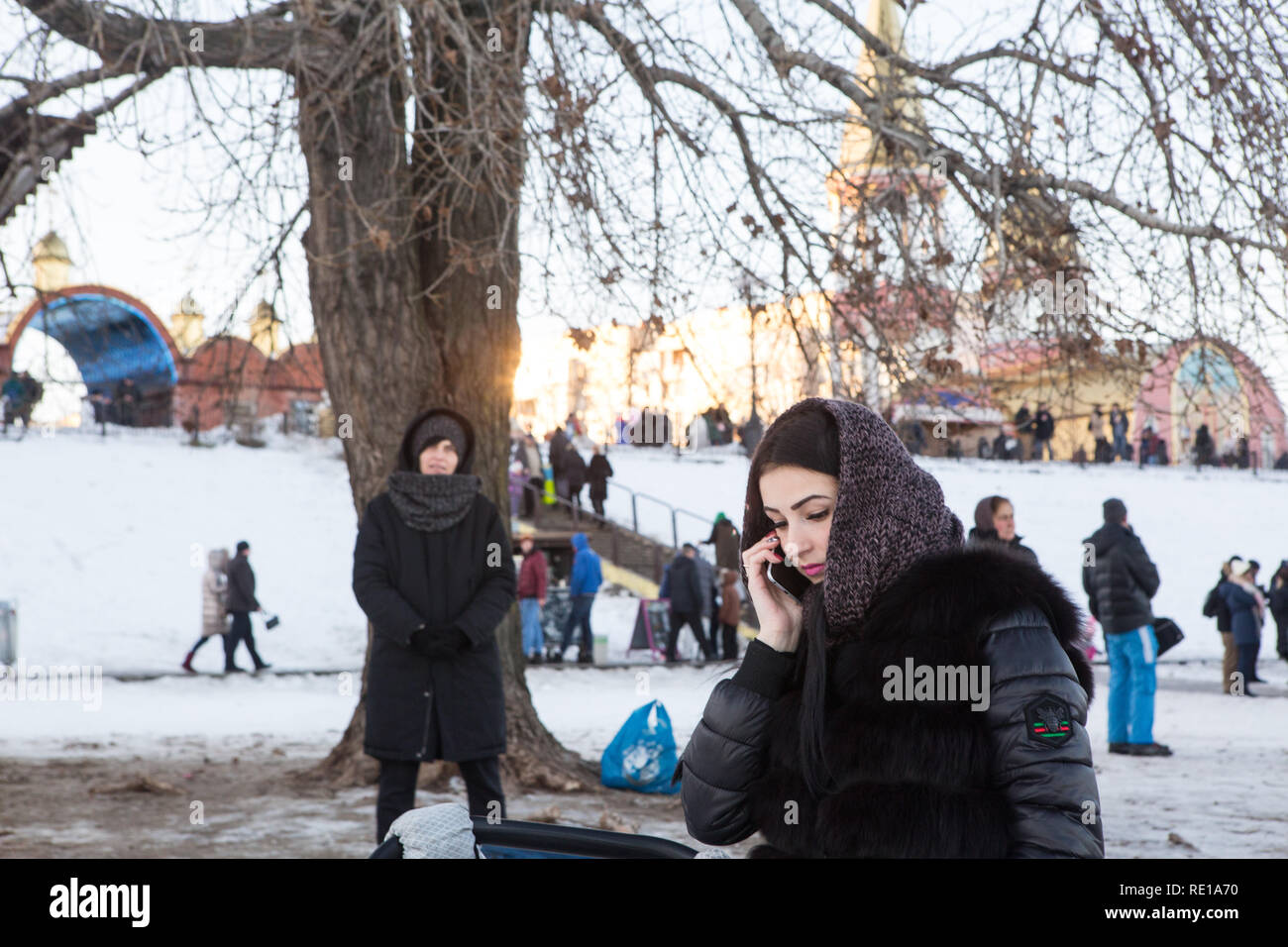 Giovane donna ucraina parla sul telefono cellulare sulla riva del fiume Dnepr a Kiev vicino a Chiesa ortodossa dove la gente locale di celebrare il battesimo dell'acqua al giorno. Foto Stock