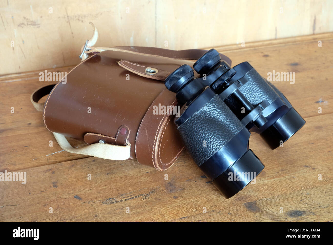 Vintage a prisma di Porro colore nero binocolo e chiuso duro Marrone una custodia in pelle su sfondo di legno vista laterale vista dettagliata per interni Foto Stock