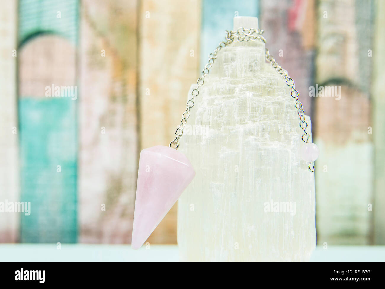 Utilizzando crystal Selenite torre di caricamento di quarzo rosa pendolo, luce tavolo blu e color pastello di legno dello sfondo. La Divinazione, fortune raccontare Foto Stock
