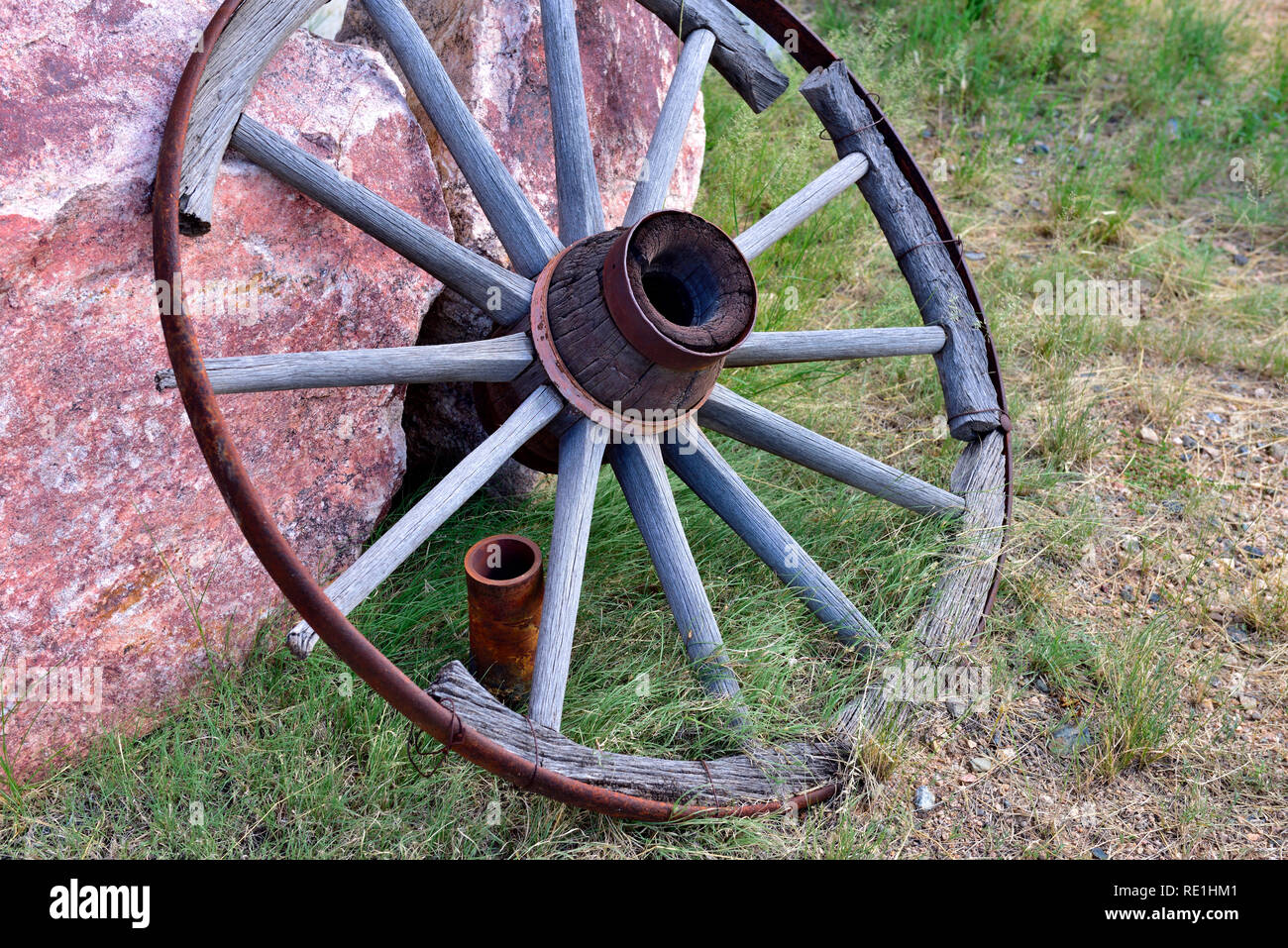 Vecchio, rotte di legno decaduto ruota del carro in appoggio contro una roccia Foto Stock