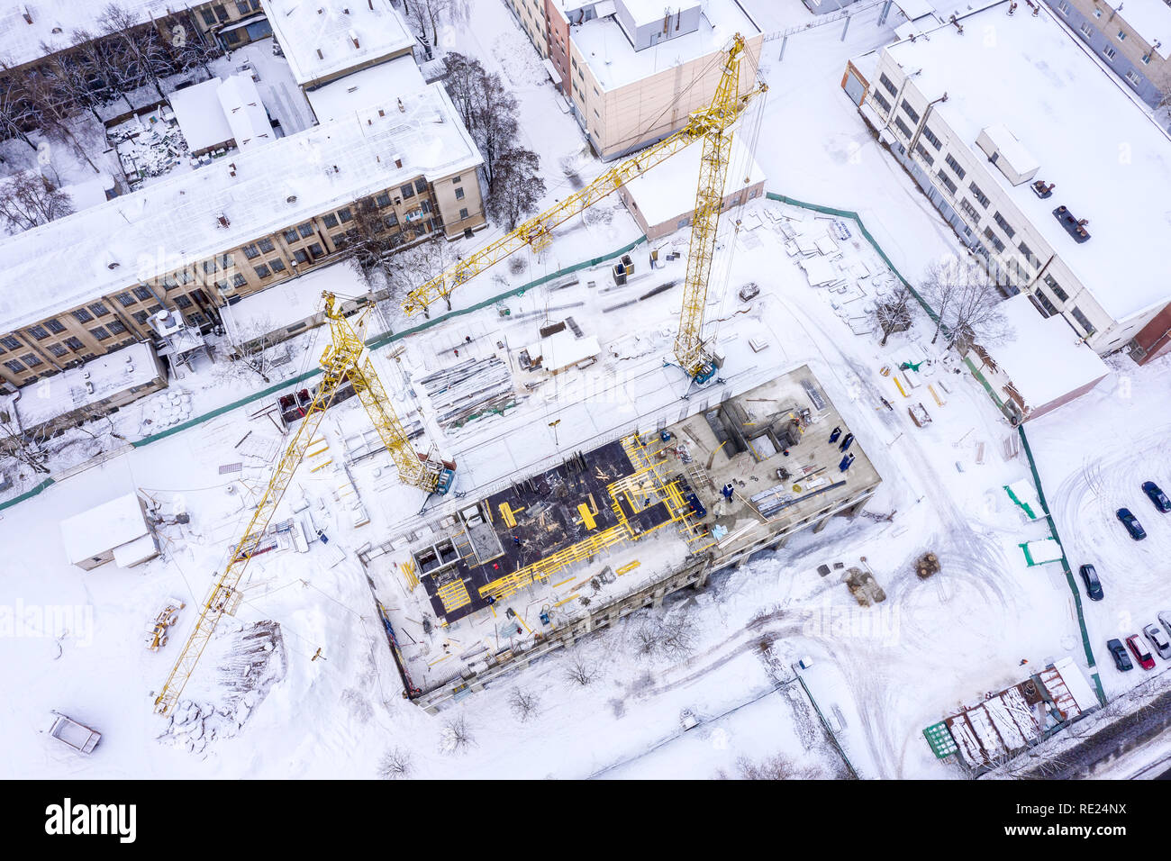 Il giallo delle gru a torre in cantiere ricoperto di neve. antenna top view image Foto Stock