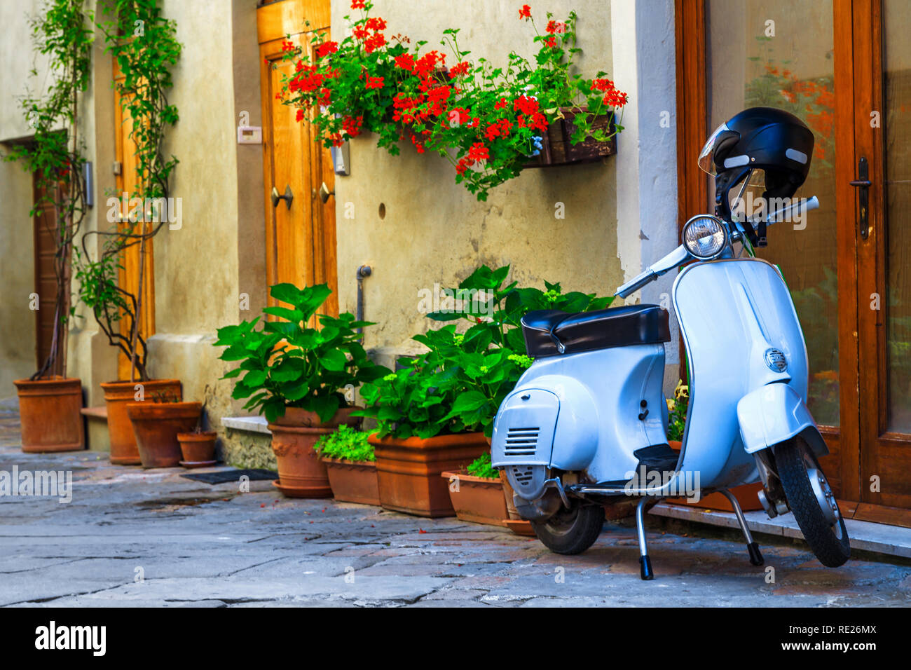 Stupendo carino strada decorata con fiori e un ingresso rustico, vecchio stile scooter in piedi in tipiche italiane street, Pienza, Toscana, Europa Foto Stock