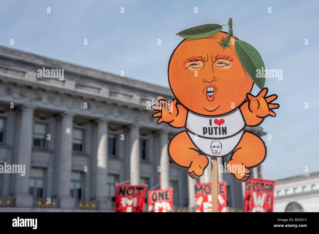San Francisco, Stati Uniti d'America. 19 gennaio, 2019. Le donne di Marzo a San Francisco inizia con un rally al Civic Center Plaza di fronte al Palazzo del Municipio. Un manifestante detiene un cartoon segno beffardo Donald Trump come un neonato che indossa un "Io amo Putin' onesie. Il presidente della testa è fatto per assomigliare ad una pesca, un probabile riferimento di impeachment. Credito: Shelly Rivoli/Alamy Live News Foto Stock