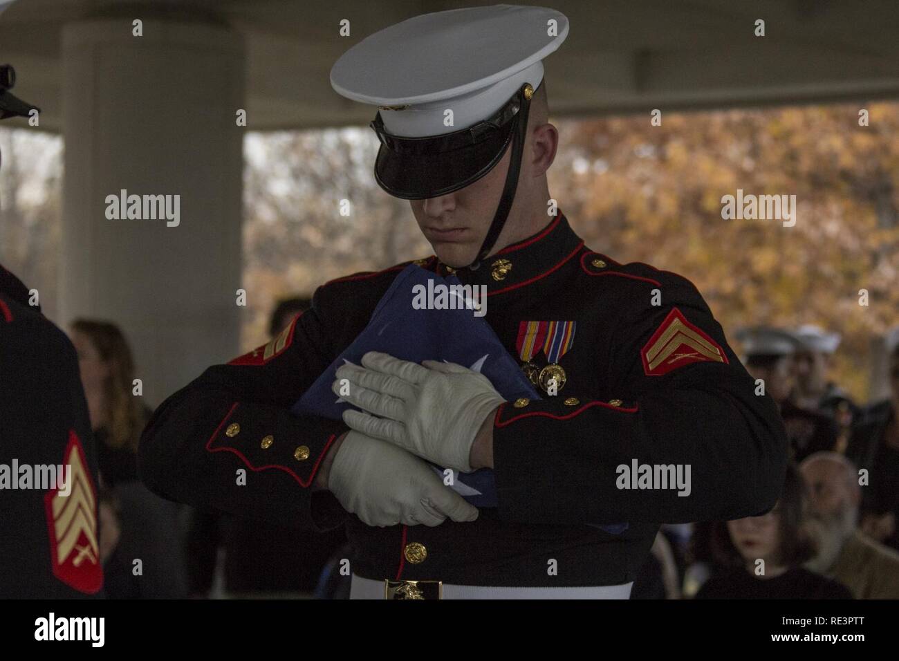 Un U.S. Marine con caserma marini Washington pieghe una bandiera americana durante il servizio funebre per James D. Gleason, U.S. Navy corpsman, presso il Cimitero Nazionale di Arlington, Arlington, Virginia, nov. 16, 2016. Gleason è creduto per essere il più giovane Navy Corpsman sia servita nella II Guerra Mondiale ed è stato una parte originale di predatore marino unità.. Foto Stock