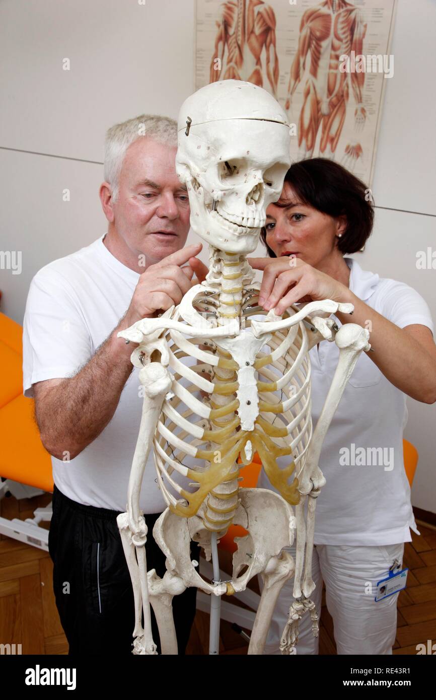Terapeuta spiegare ad un paziente sulla base di uno scheletro di base anatomica per un trattamento di fisioterapia, fisico Foto Stock