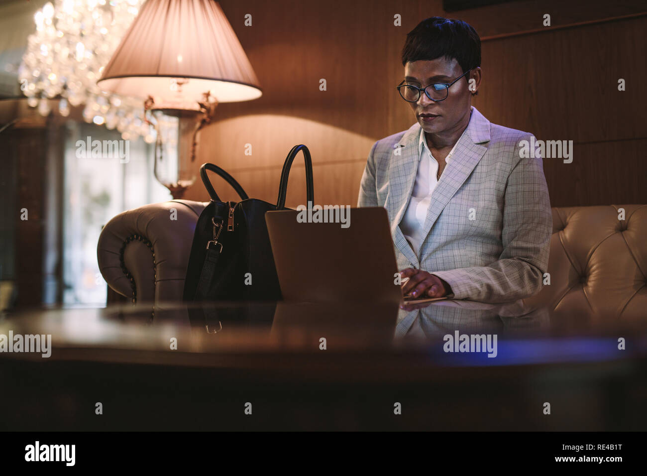 Coppia donna africana seduti alla reception di hotel lettino e di lavoro sul computer portatile. Il CEO di sesso femminile in viaggio d'affari con computer portatile nella hall dell'hotel. Foto Stock