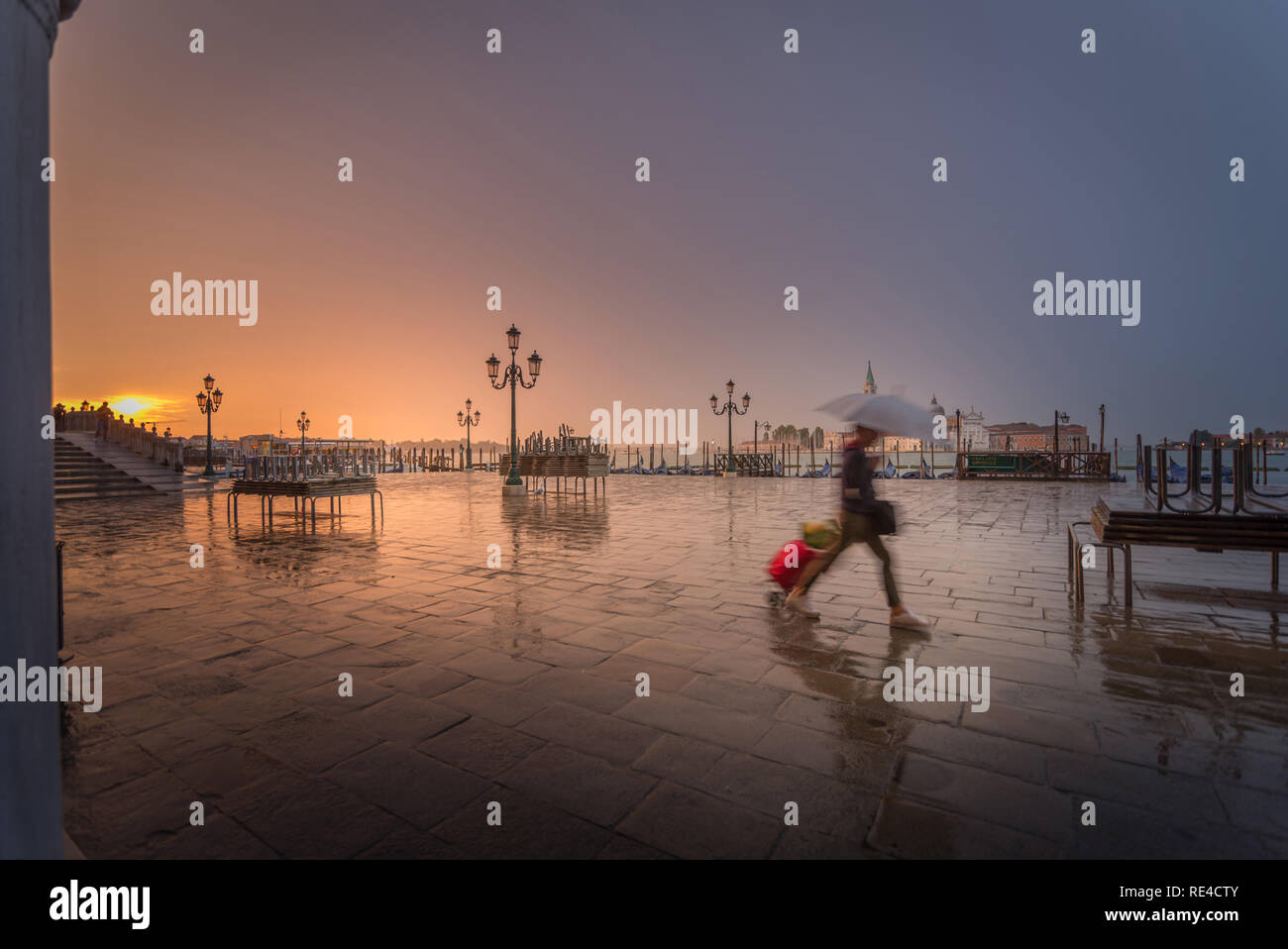 Una ragazza in fretta di pioggia la mattina presto con la valigia Foto Stock