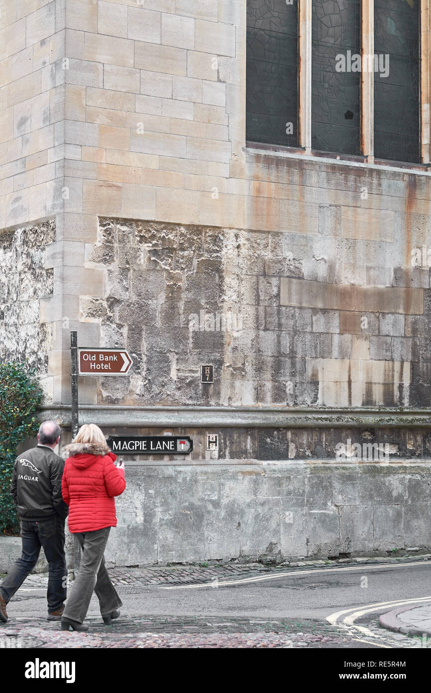 Un uomo e una donna a piedi lungo la strada in corrispondenza di un angolo della Gazza Lane, accanto alla parete della cappella di Oriel college, università di Oxford, Inghilterra. Foto Stock