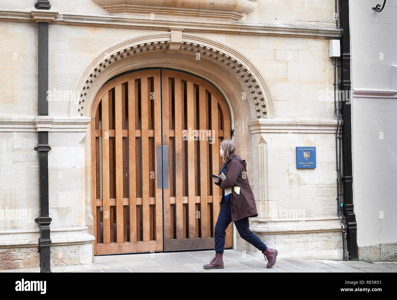 Una studentessa passeggiate ammirando il gateway ingresso al Jackson e Oldham edifici del Corpus Christi College, Università di Oxford, Inghilterra. Foto Stock