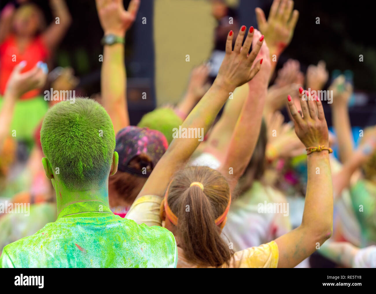 Giovani mans hans in aria in un colore fest con polvere di colore giallo. Divertente e gioiosa festa di colori in questo momento. Giovani godendo del tempo insieme. Foto Stock